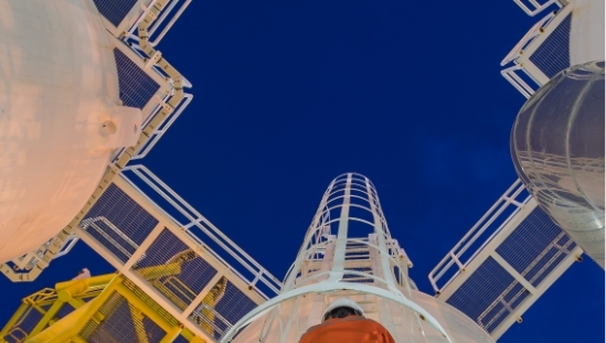 Voimalaitoksen työntekijä kiipeää tikkaita